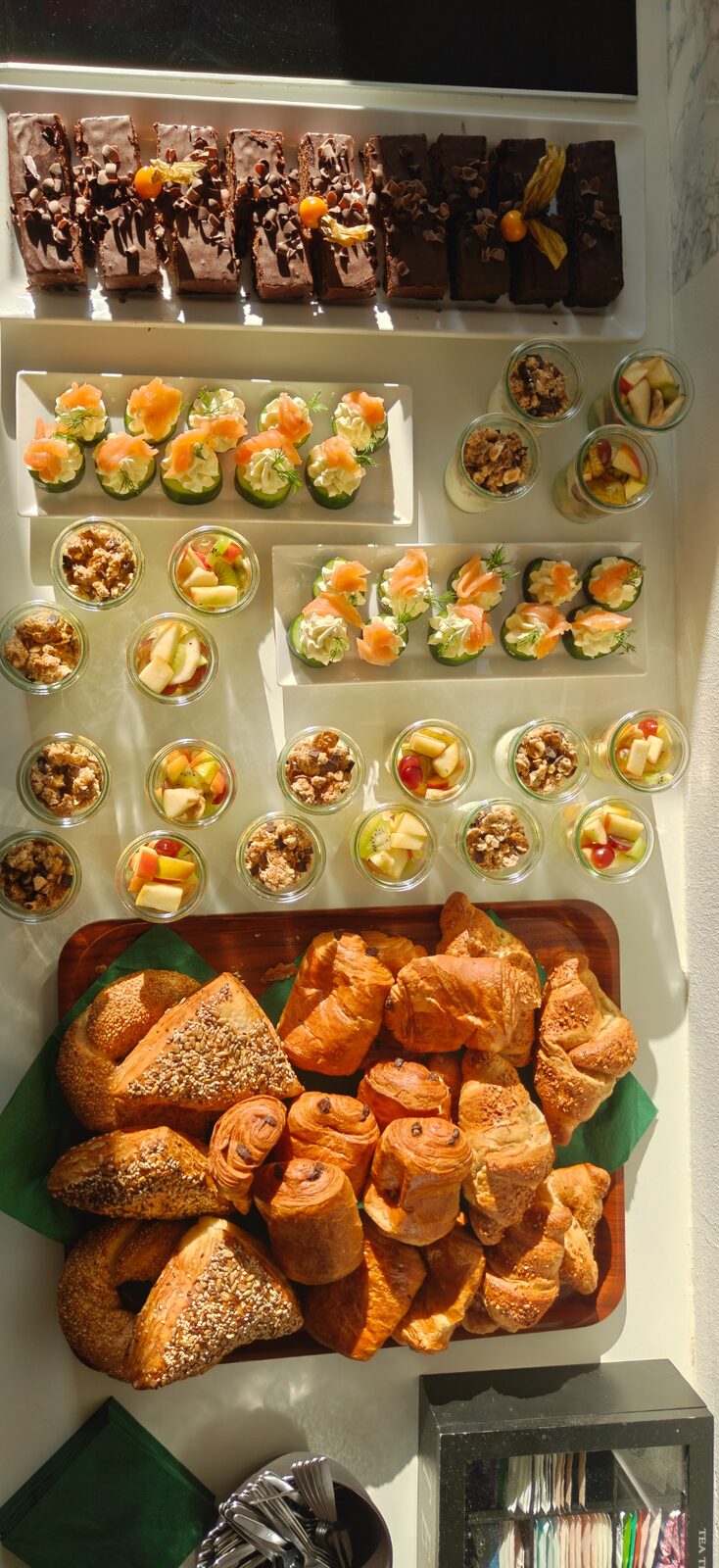 Frühstücksbuffet im Sonnenlicht mit Brownies, Gebäck und Obstgläsern